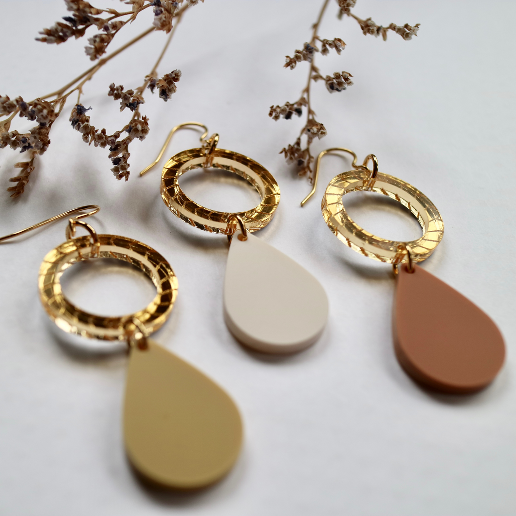 Neutral pendant dangles with gold circles